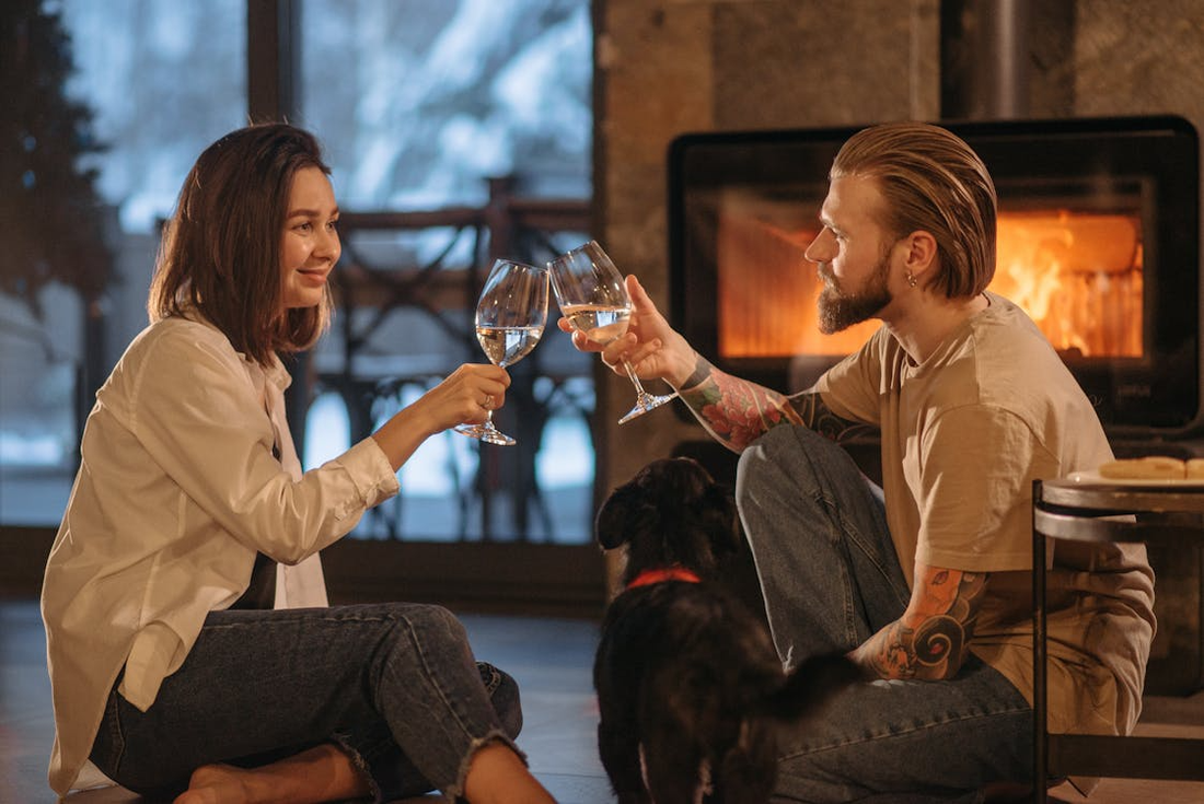 Cozy winter scene with glasses of red and white wine beside a fireplace